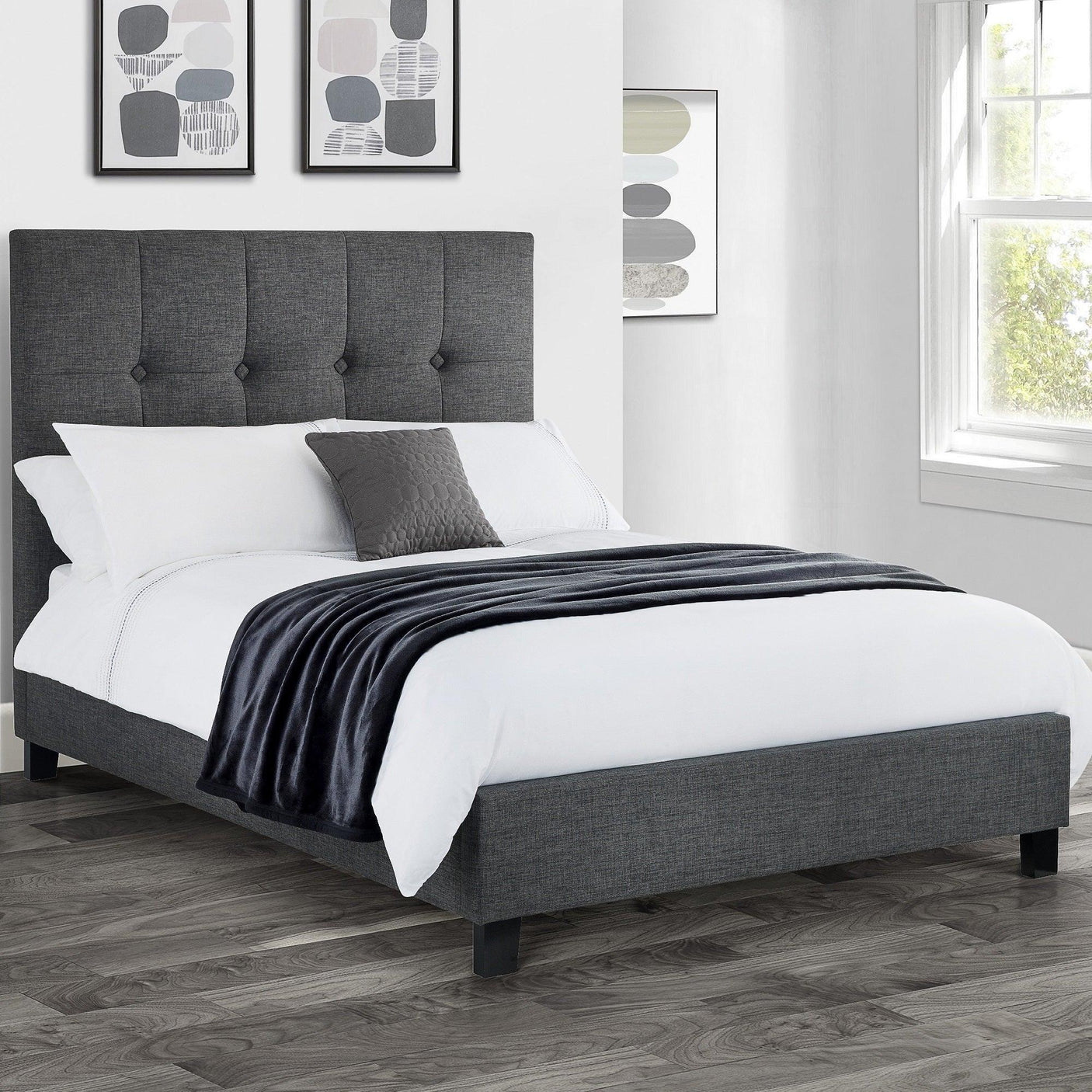 Grey fabric upholstered bed with high buttoned headboard in bright bedroom