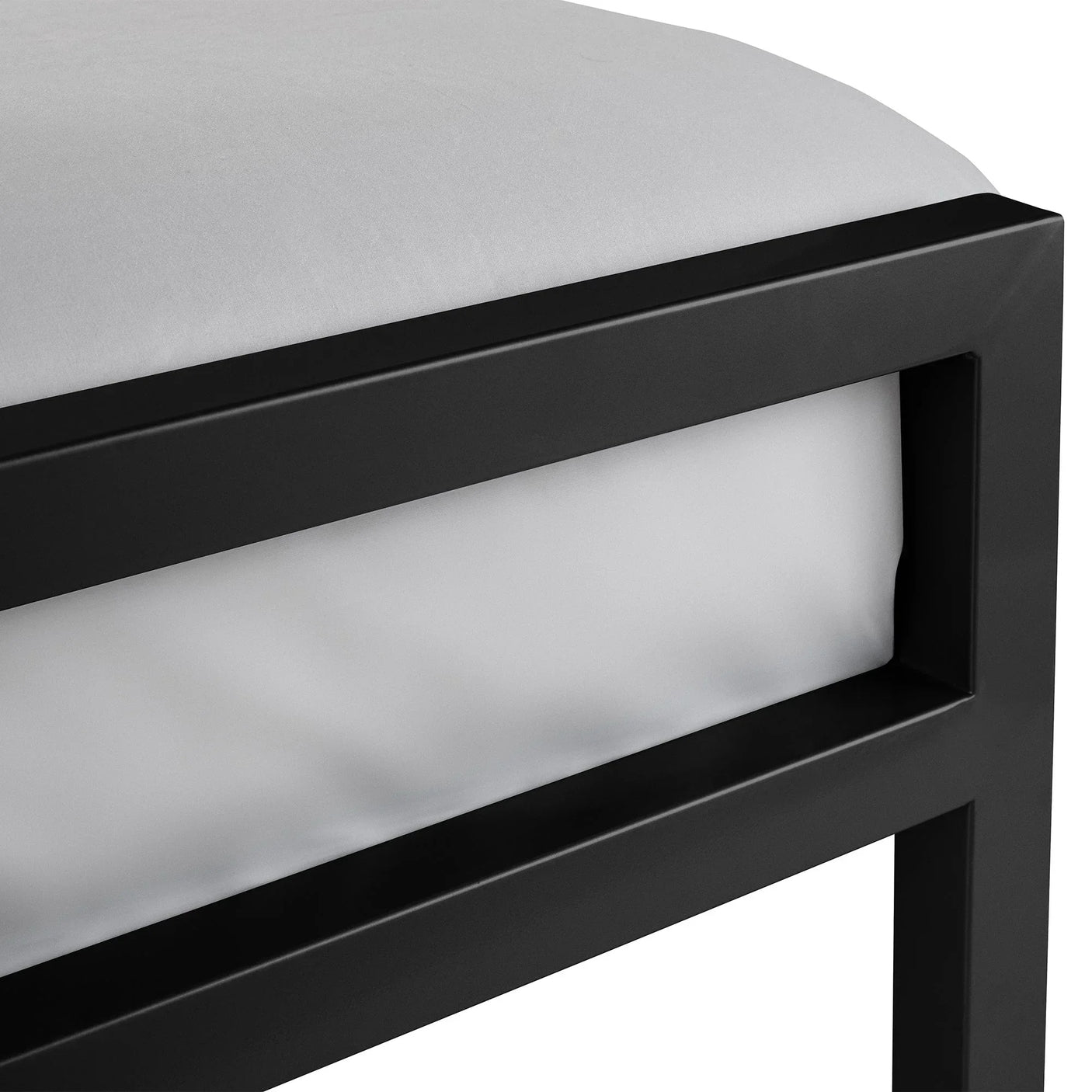 Close-up of black metal bed frame corner with white mattress
