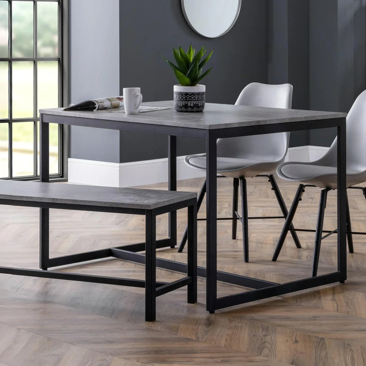Grey dining table set with black metal frame, matching bench and white chairs in modern room