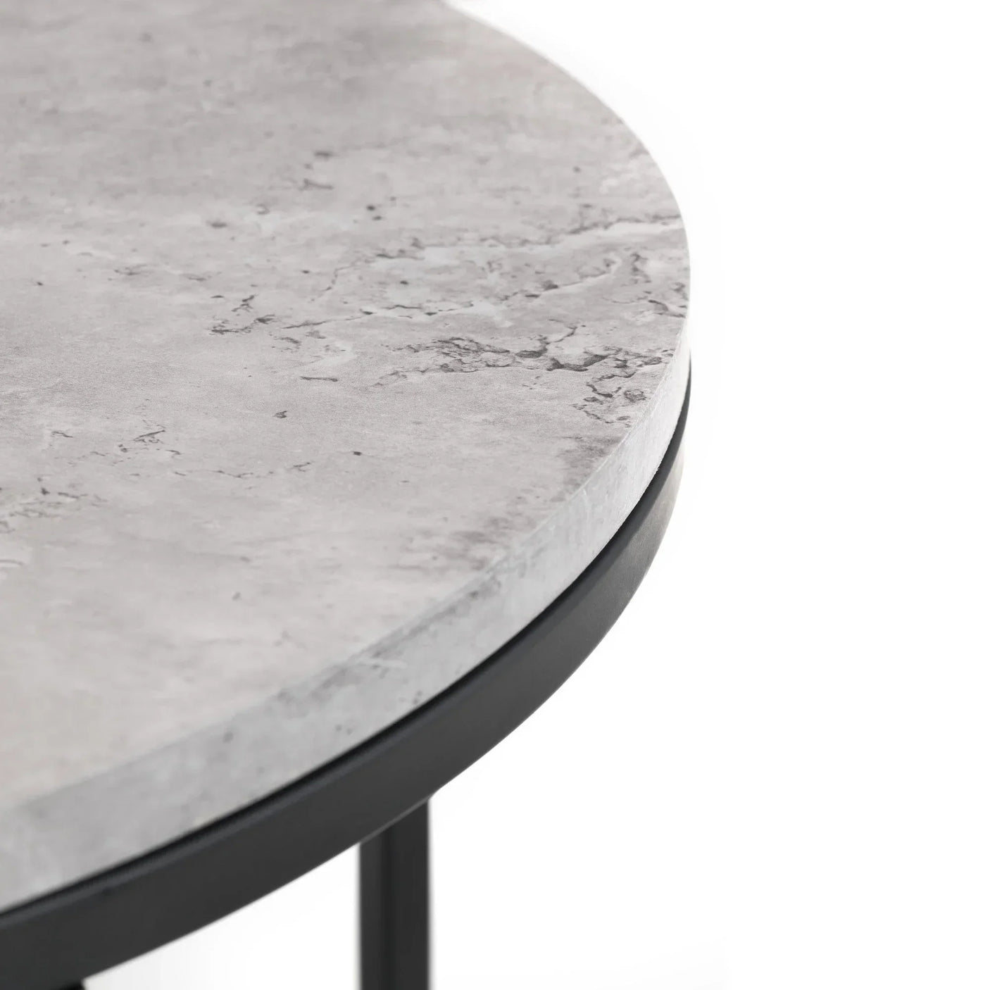 Closeup of round nesting coffee table with grey stone effect top and black metal frame
