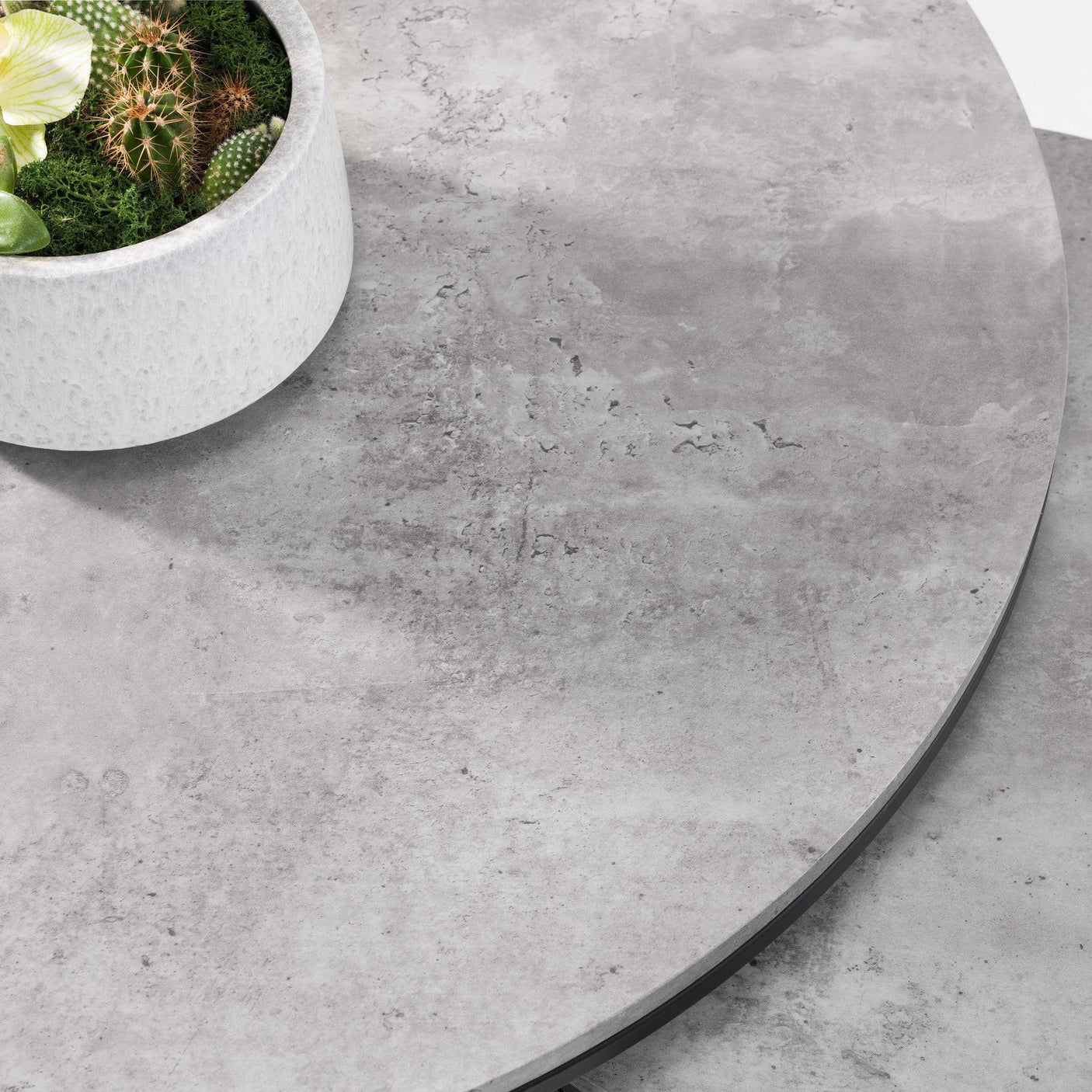 Round nesting coffee table with concrete finish and plant in white pot