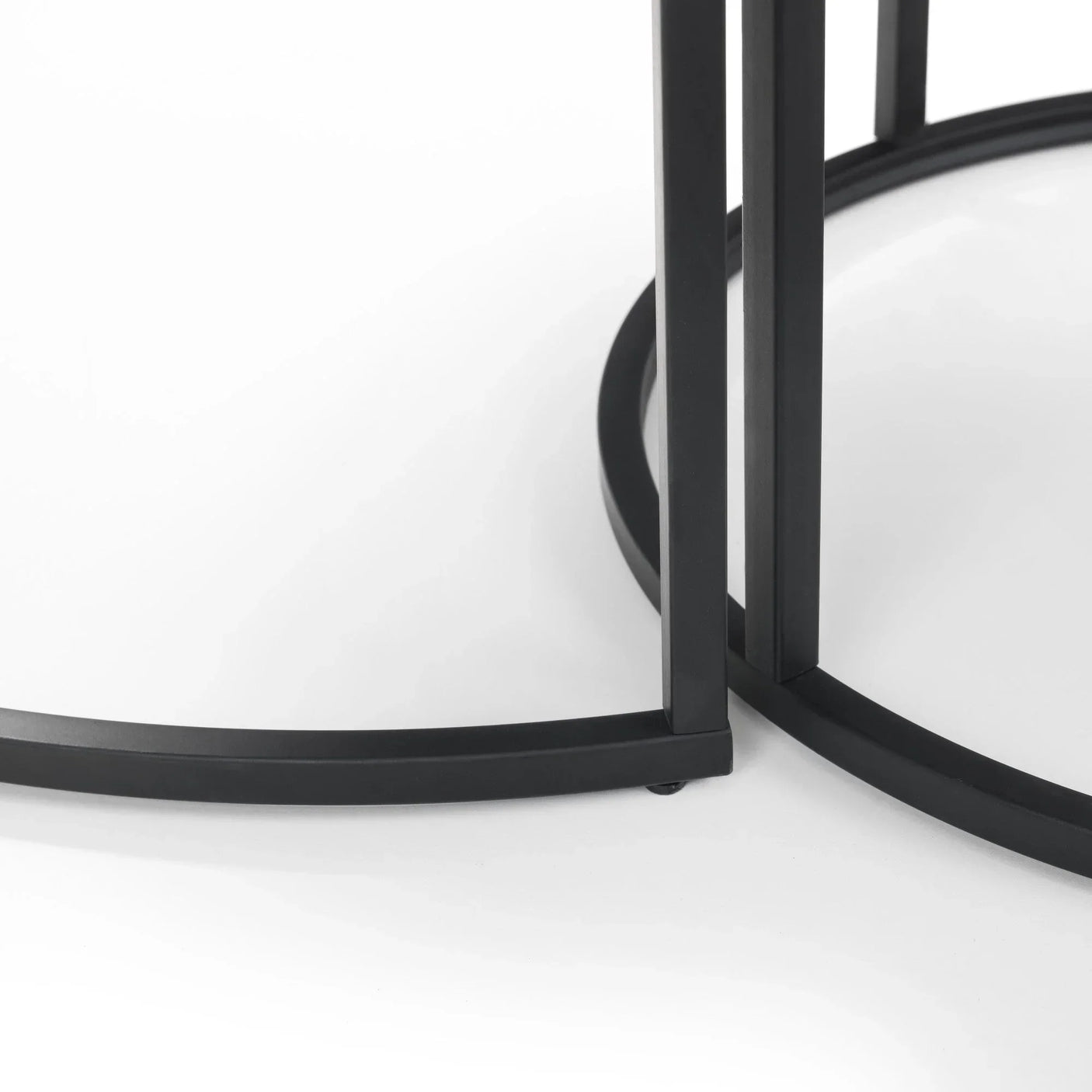 Black metal base detail of round nesting coffee tables on white background