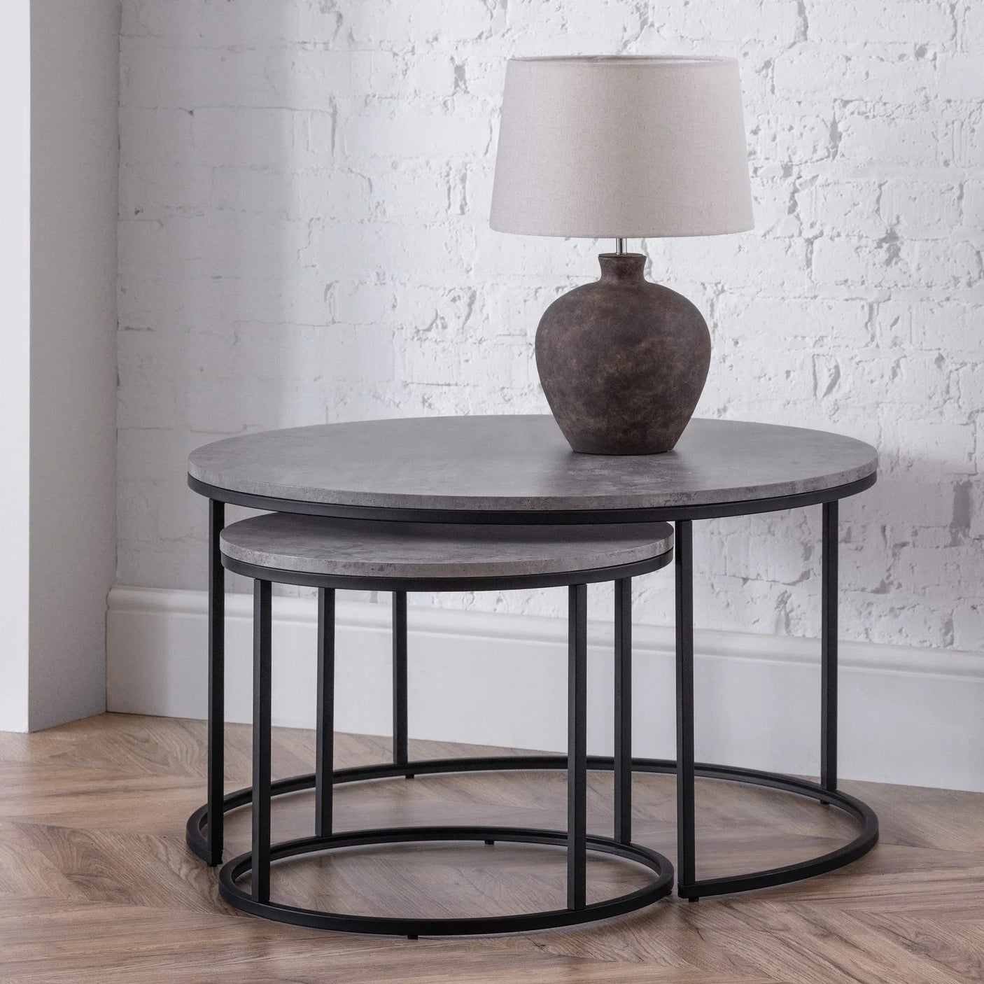 Round nesting coffee tables with black metal frames and grey tabletops in modern room