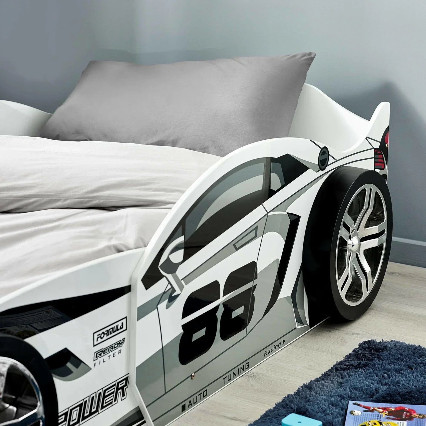 White racing car bed with number 88 side design, grey bedding, chrome effect wheel feature