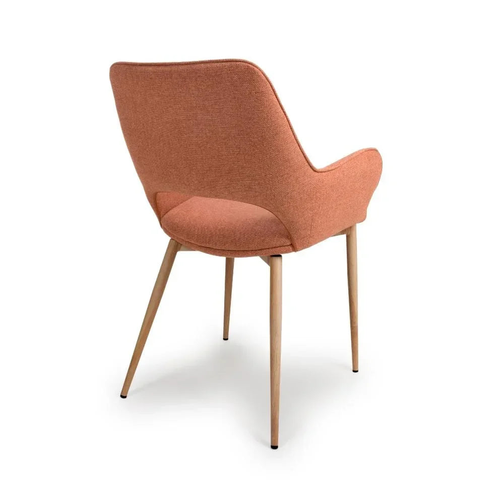 Mid-century style dining chair with orange fabric upholstery and angled wooden legs, rear view