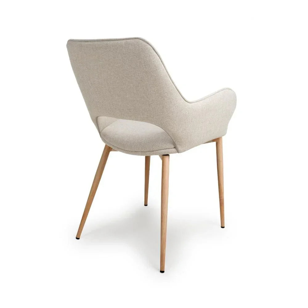 Beige upholstered dining chair with curved backrest and wooden legs, rear angle view