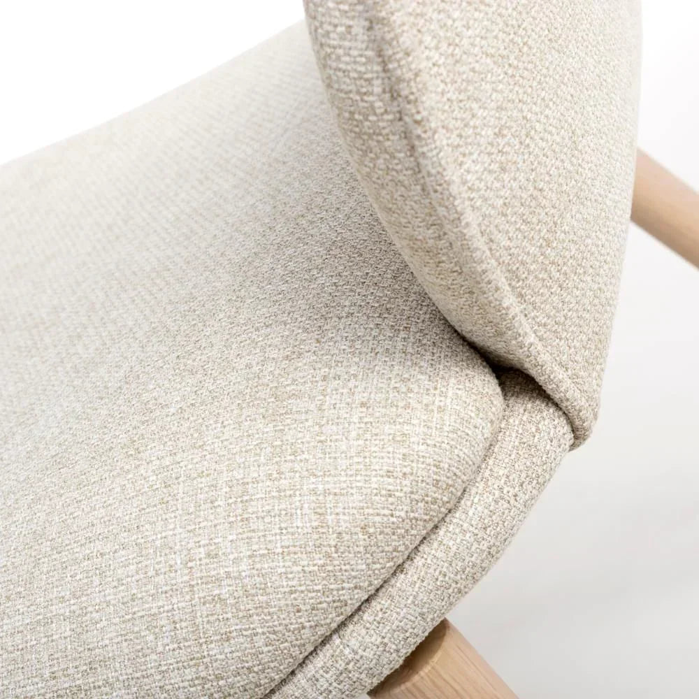 Close-up of beige fabric dining chair seat and backrest with light wood legs
