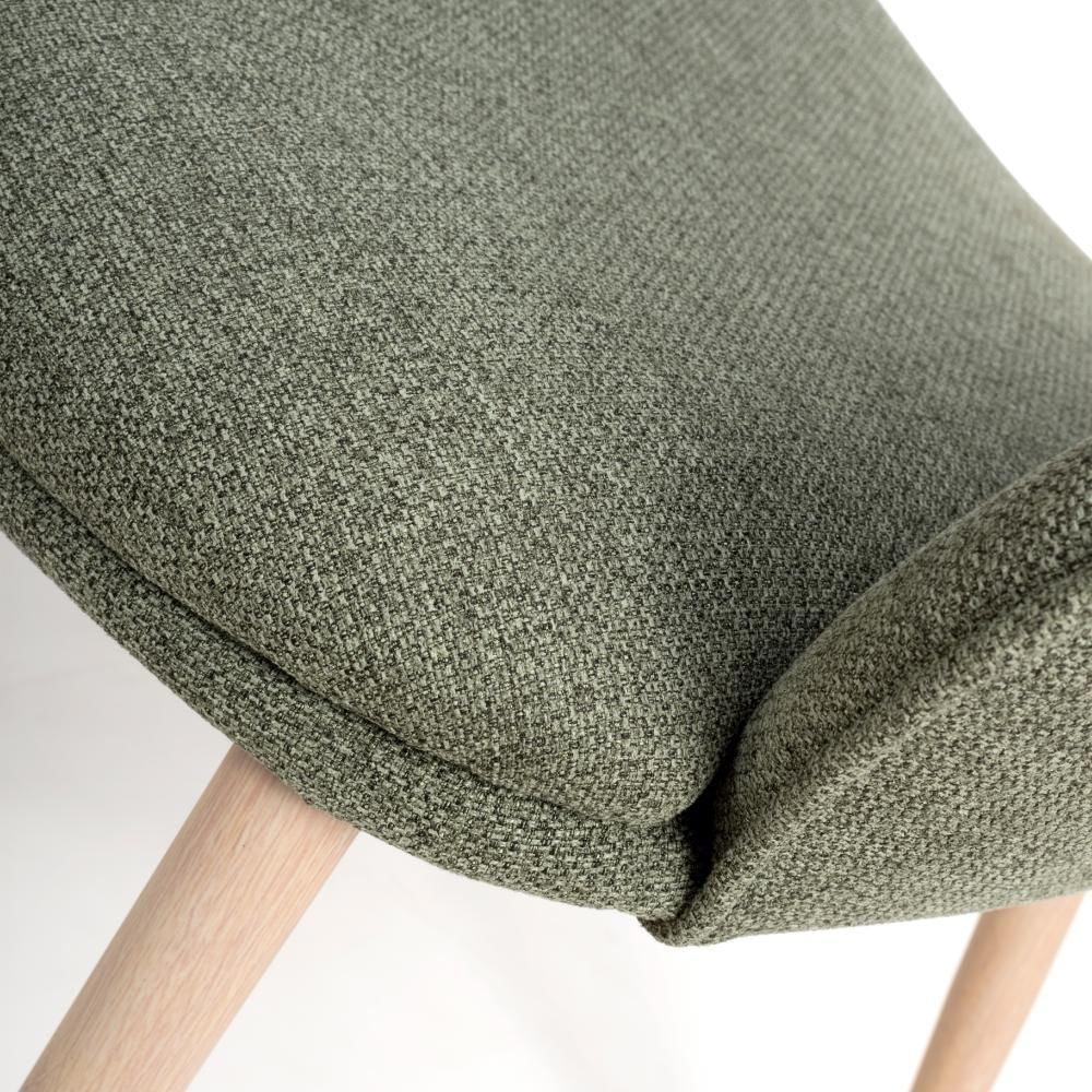 Close up of green fabric dining chair seat with light wooden legs