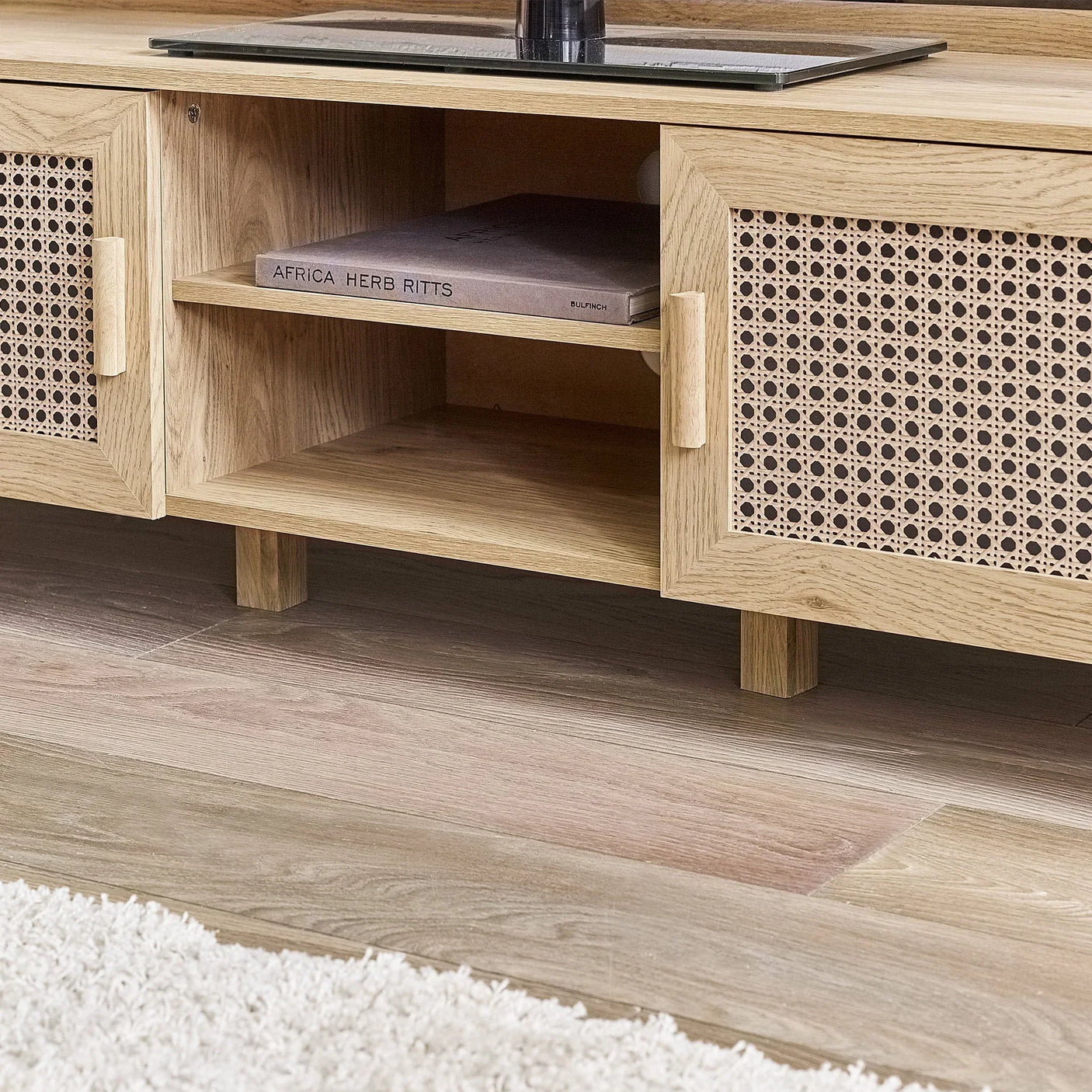 Rattan effect media unit with wooden finish and open shelf detail on wood flooring