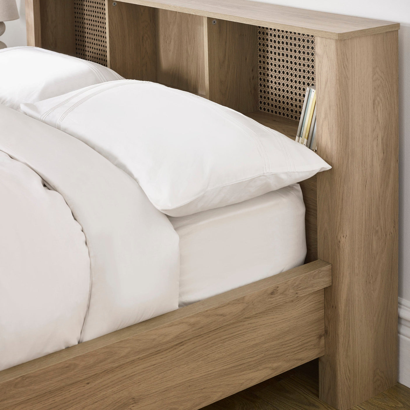 Close-up of woven rattan detail in oak wood headboard with white pillow and bedding