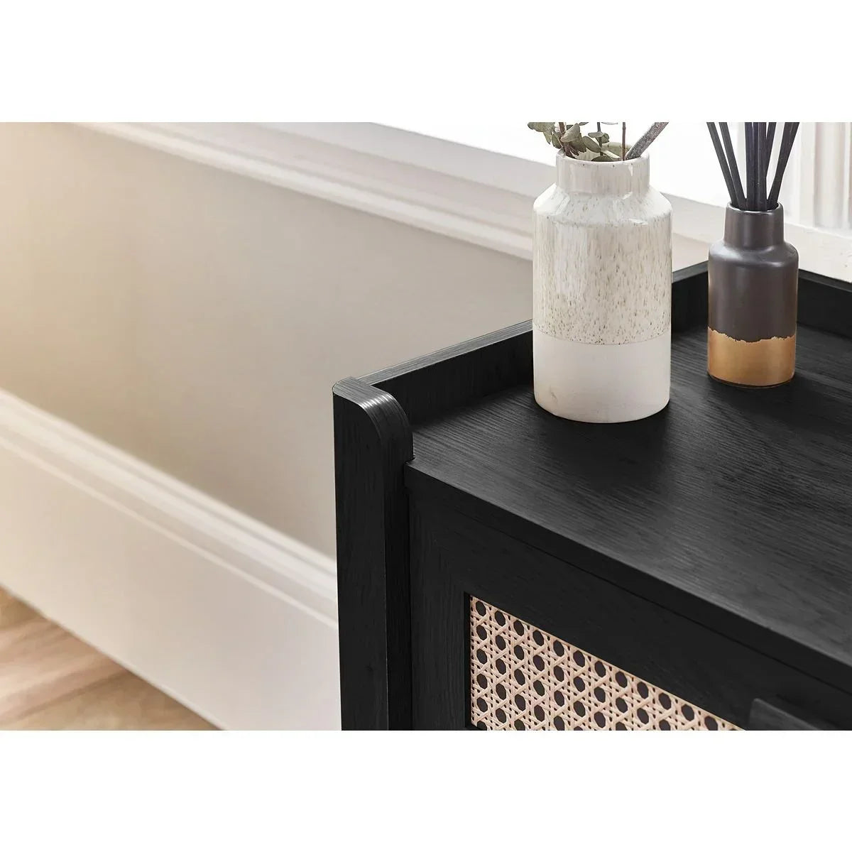 Black wood sideboard with rattan panel and decorative vases on top