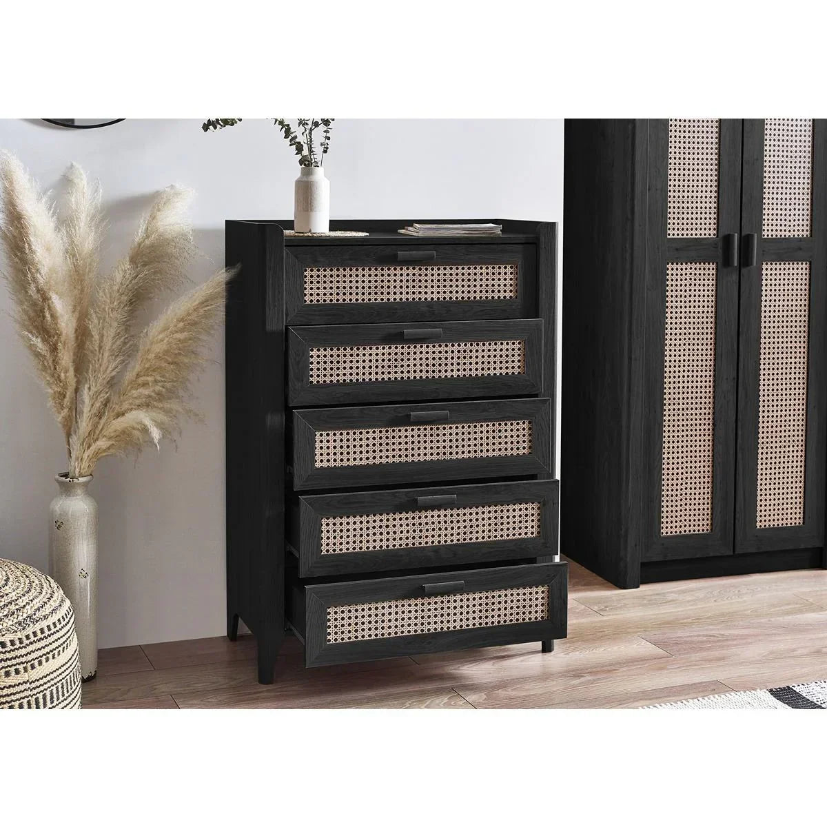 Black rattan chest of drawers with cane panels in modern bedroom interior