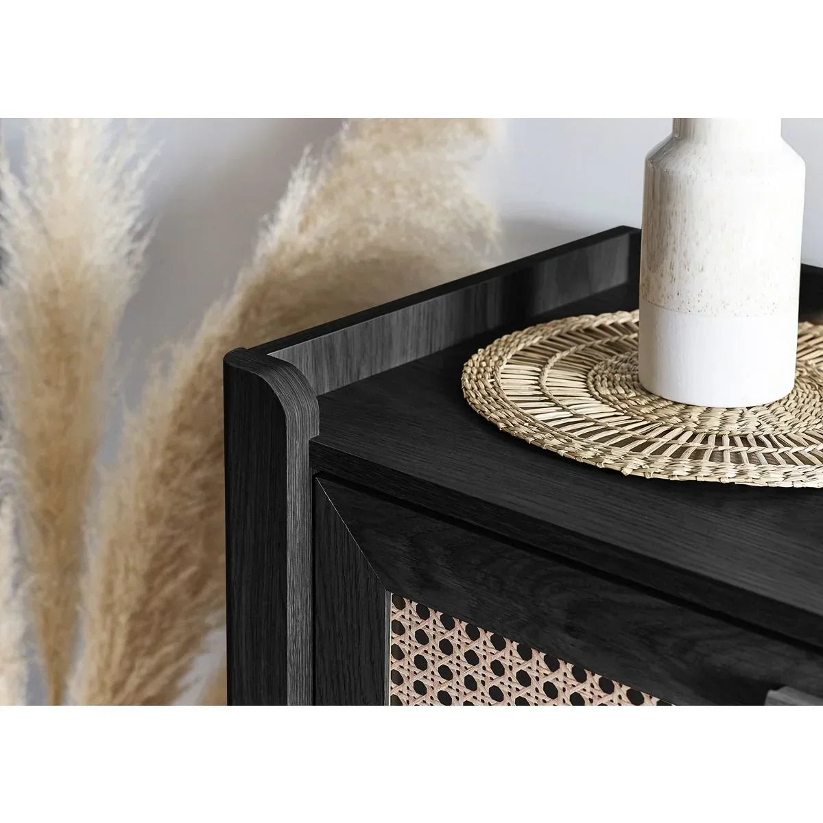 Black wood sideboard with rattan detail, decorative vase and woven placemat on top