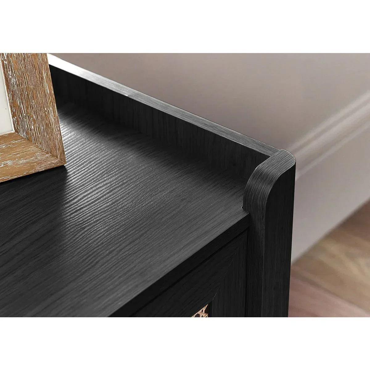 Closeup of black wood sideboard corner with textured finish and raised edge detail