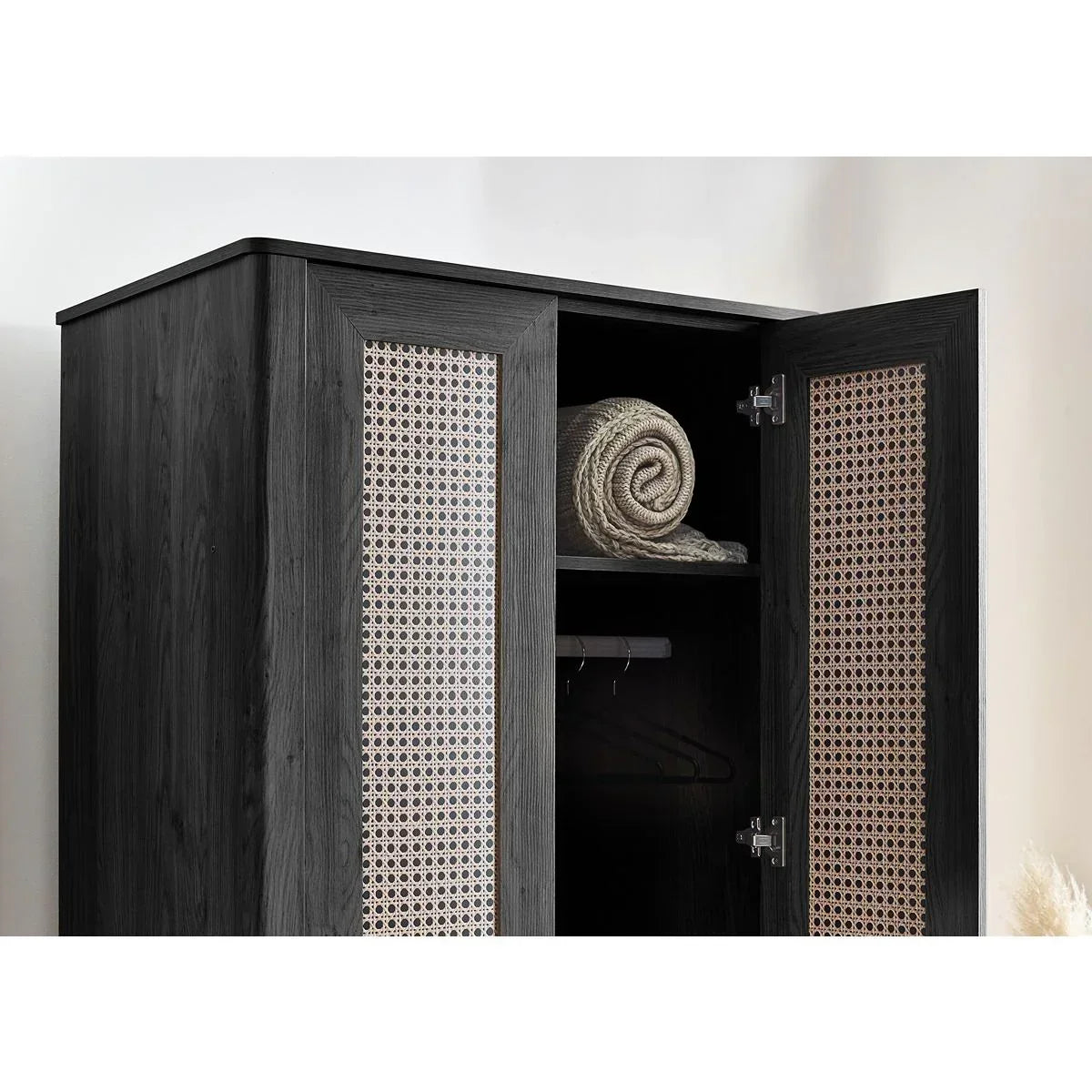 Black wood wardrobe with open rattan doors and shelf, showing a rolled throw blanket inside