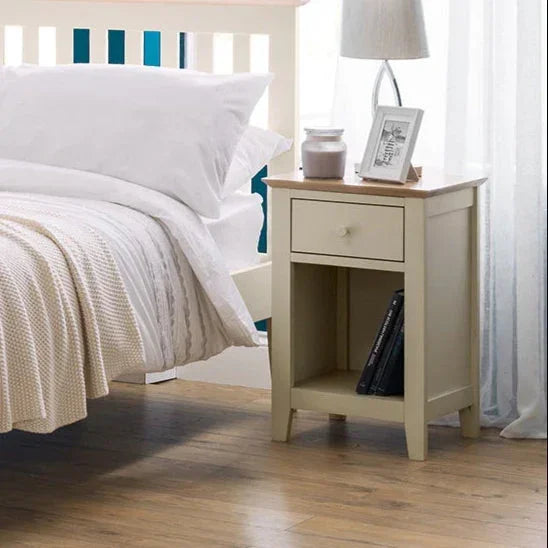 Two-tone wooden bedside table with drawer next to bed, styled with lamp and decor