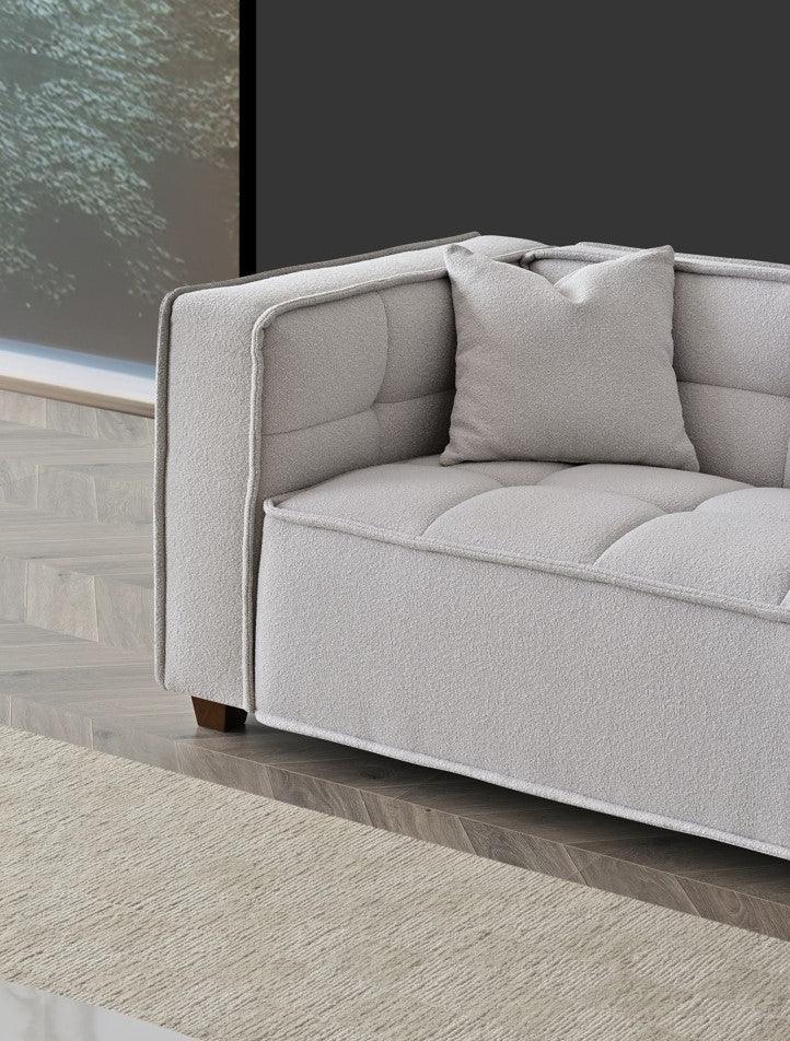 Modern light grey fabric sofa with matching cushion on wooden flooring