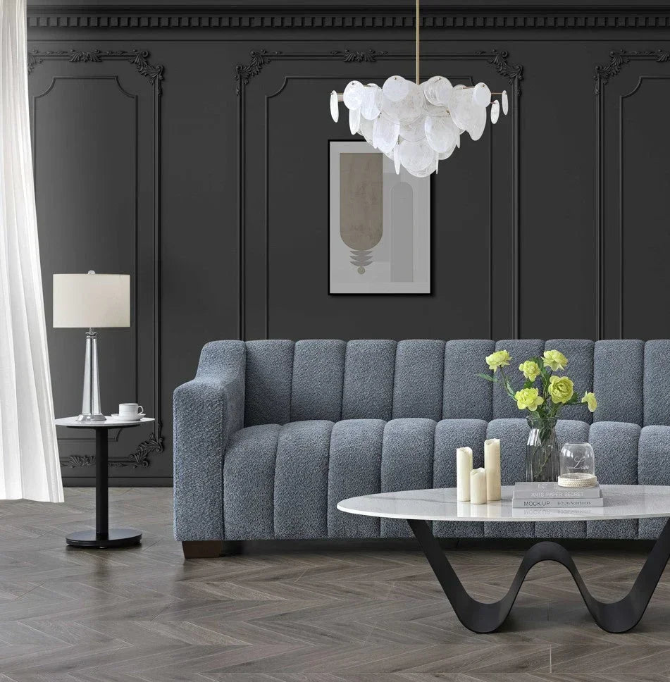Grey textured sofa with vertical channels, marble coffee table, black panel wall, modern decor