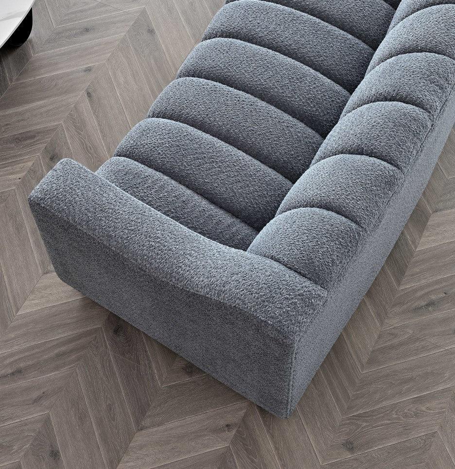 Grey textured fabric sofa with channel tufting on chevron wood floor