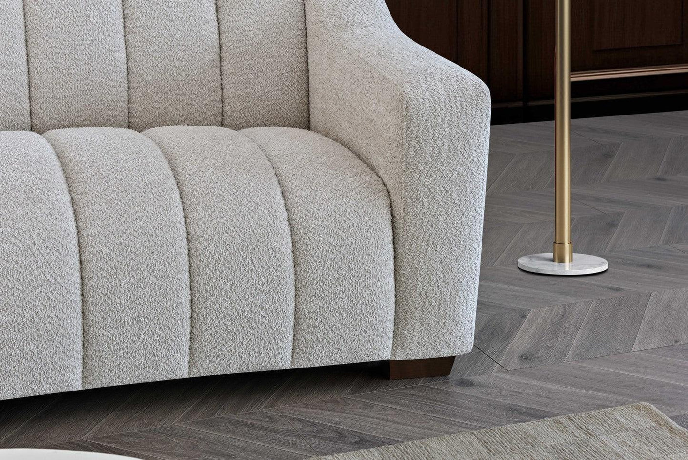 Ivory boucle sofa with channel tufted upholstery and angular armrest on wooden floor