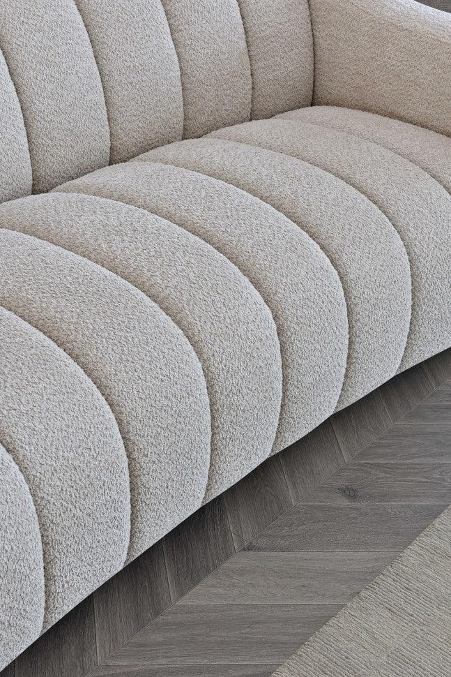 Beige textured sofa with channel tufting on wood floor