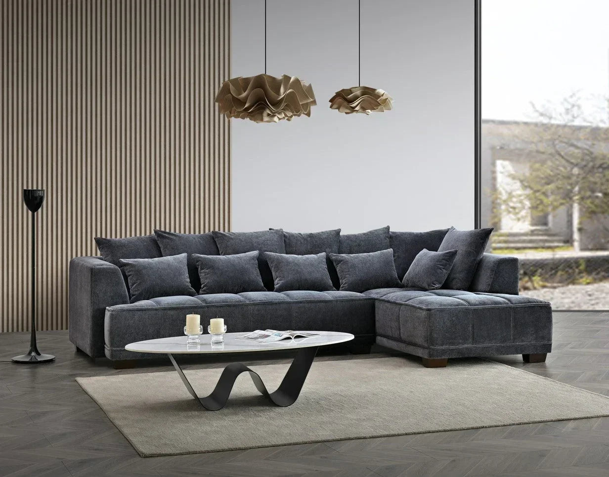 Dark grey corner sofa with scatter cushions in modern living room, coffee table in foreground