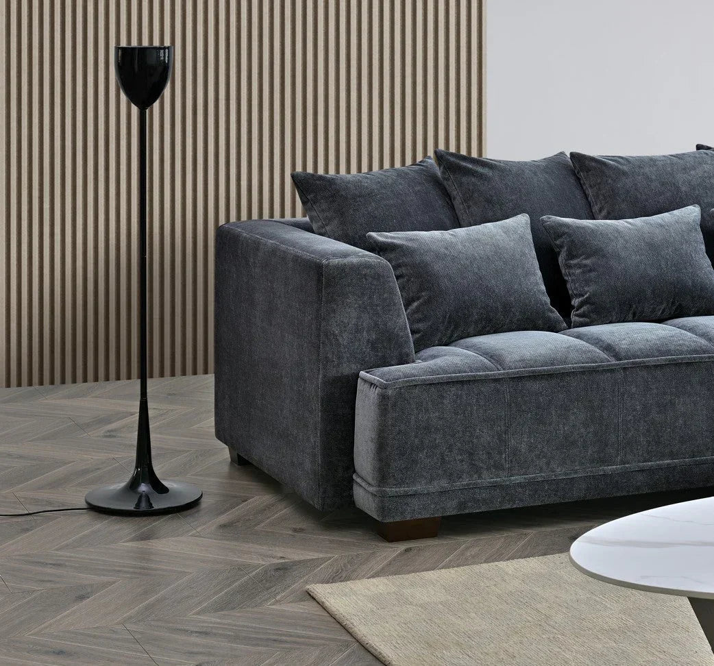 Charcoal fabric sofa with scatter cushions beside black floor lamp on wooden floor