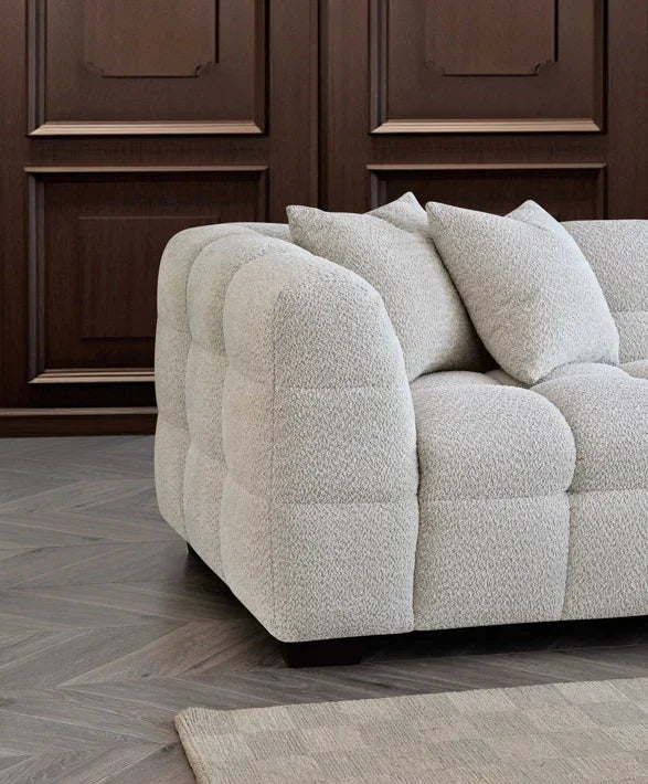 Textured cream fabric sofa with square tufted design and scatter cushions in modern room