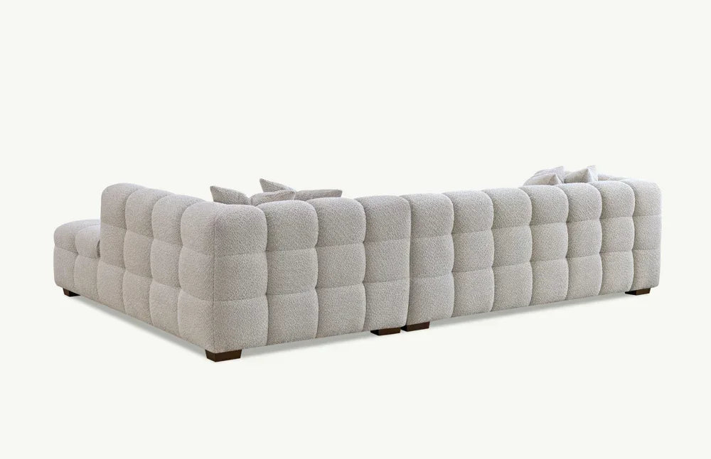 Light grey corner sofa with tufted upholstery and low block feet, rear angle view