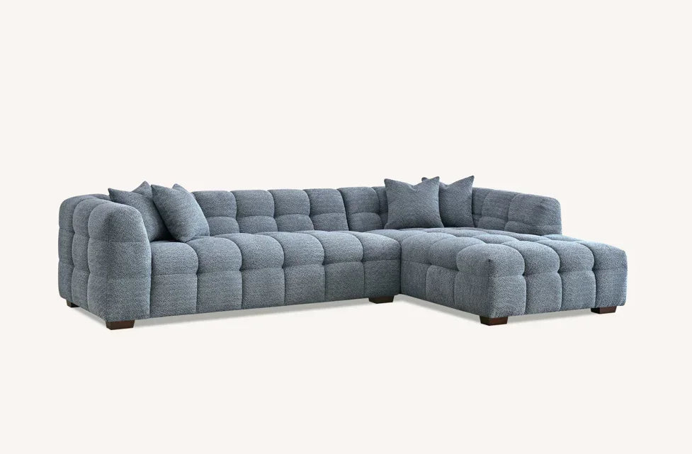 Grey fabric corner sofa with tufted design and scatter cushions on wooden feet