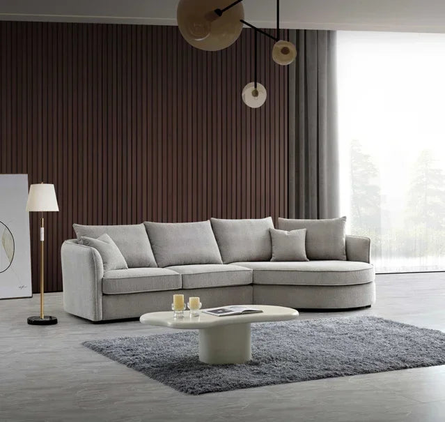 Light grey corner sofa with curved chaise in modern living room on grey rug