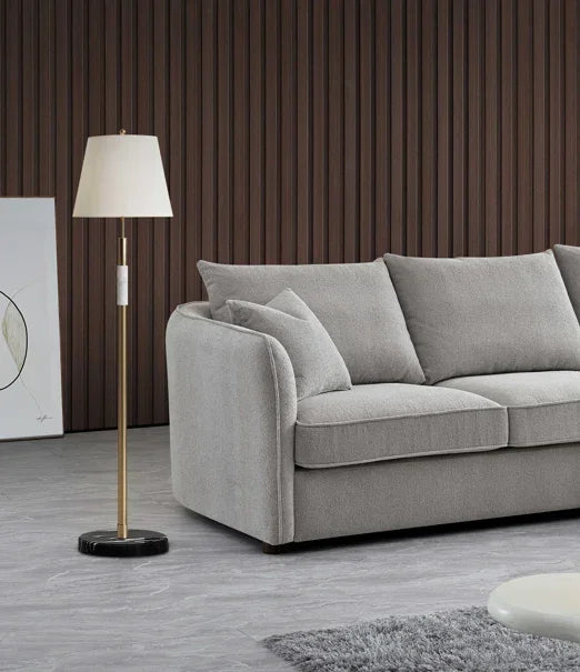 Grey fabric sofa with matching cushions beside brass floor lamp in modern living room