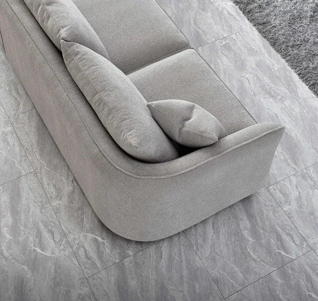 Grey fabric sofa with curved armrest and cushions on tiled living room floor