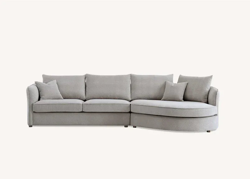 Light grey corner sofa with chaise lounge and scatter cushions on neutral background