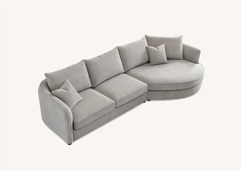 Light grey fabric corner sofa with rounded chaise and scatter cushions