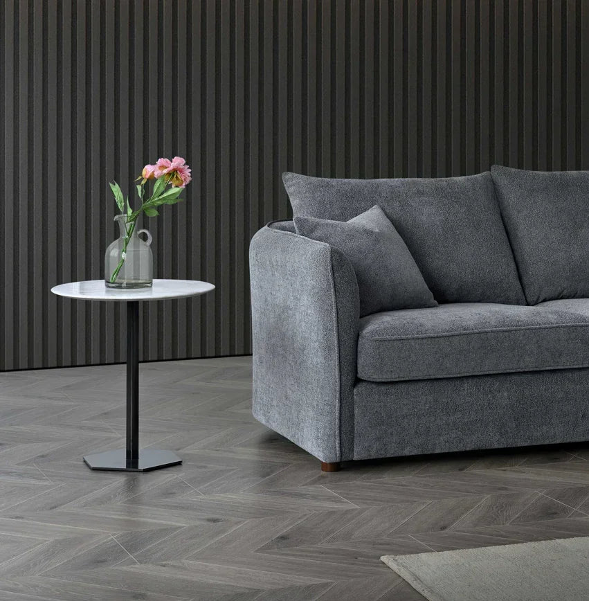 Grey fabric sofa with matching cushions beside round marble side table and vase with flowers