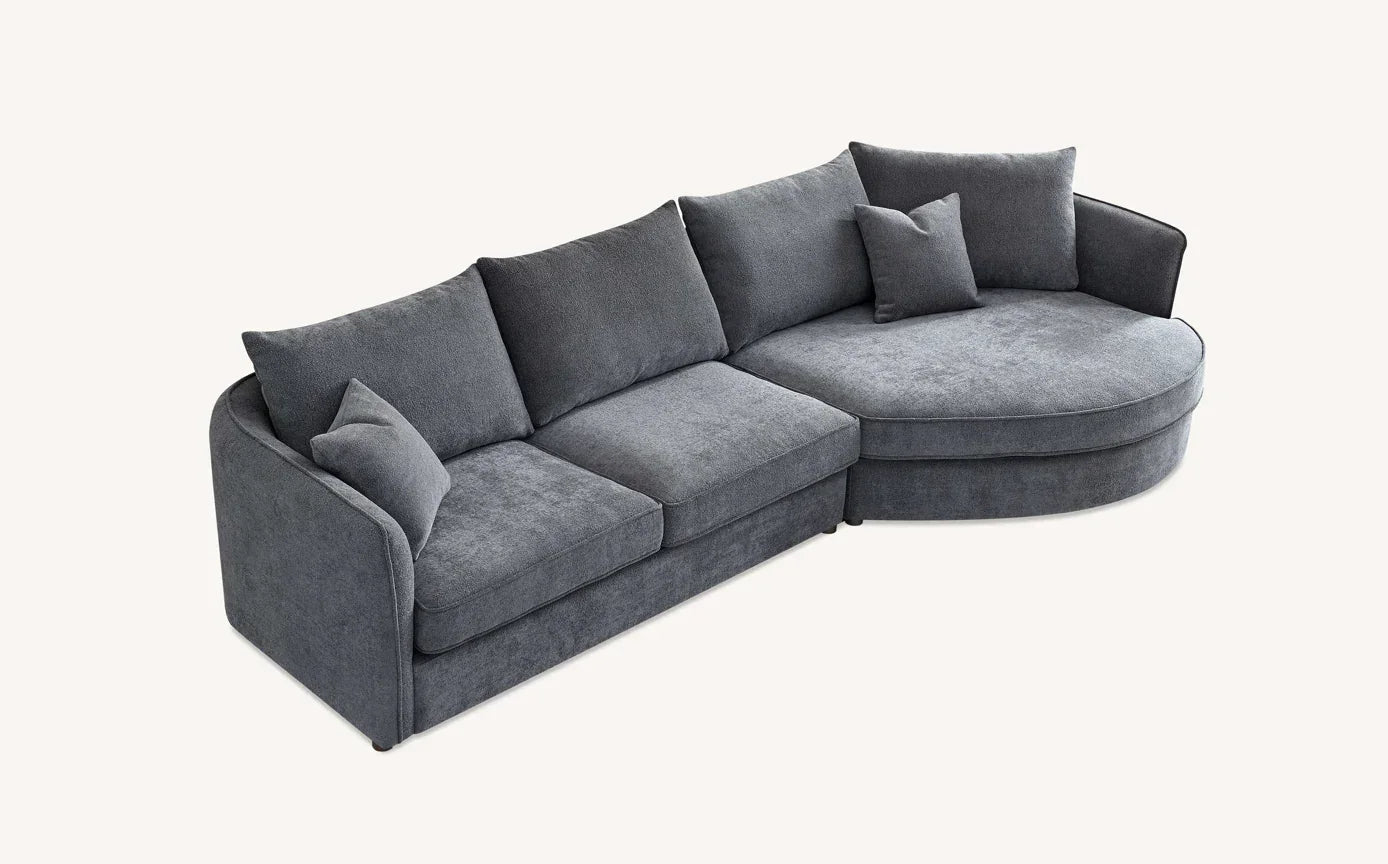 Grey corner sofa with chaise, plush fabric upholstery, scatter cushions, left-facing angle