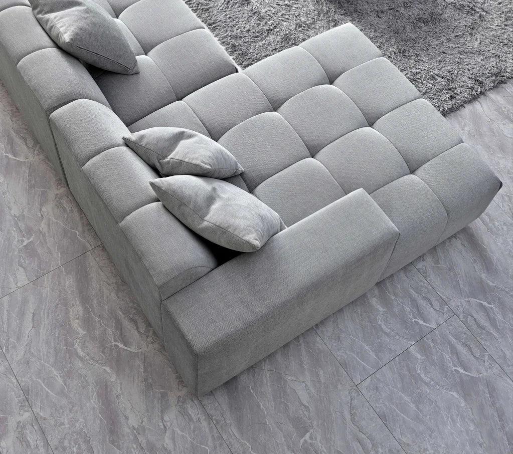 Modern grey fabric sofa with tufted cushions and matching pillows on tiled floor