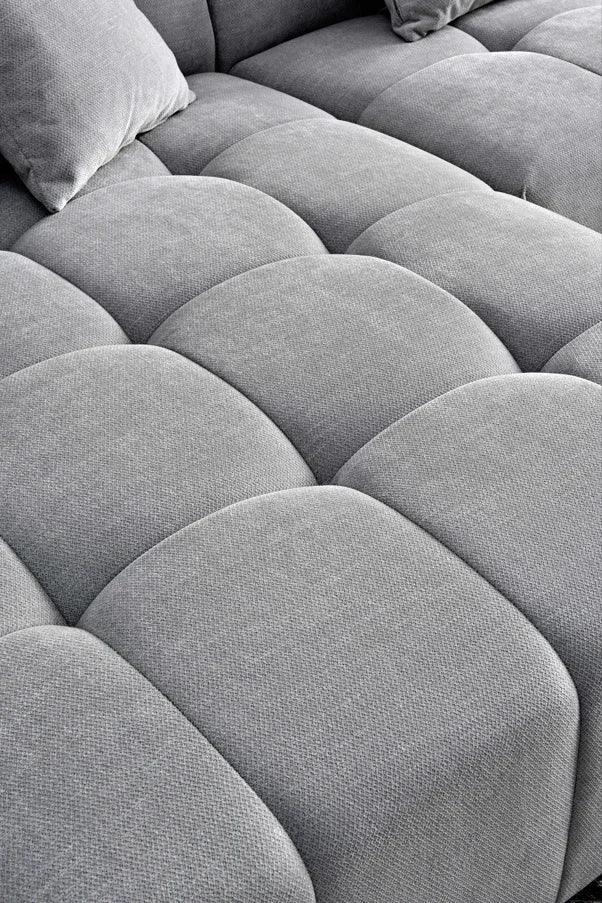 Closeup of grey fabric sofa seat with tufted cushion design and matching pillow