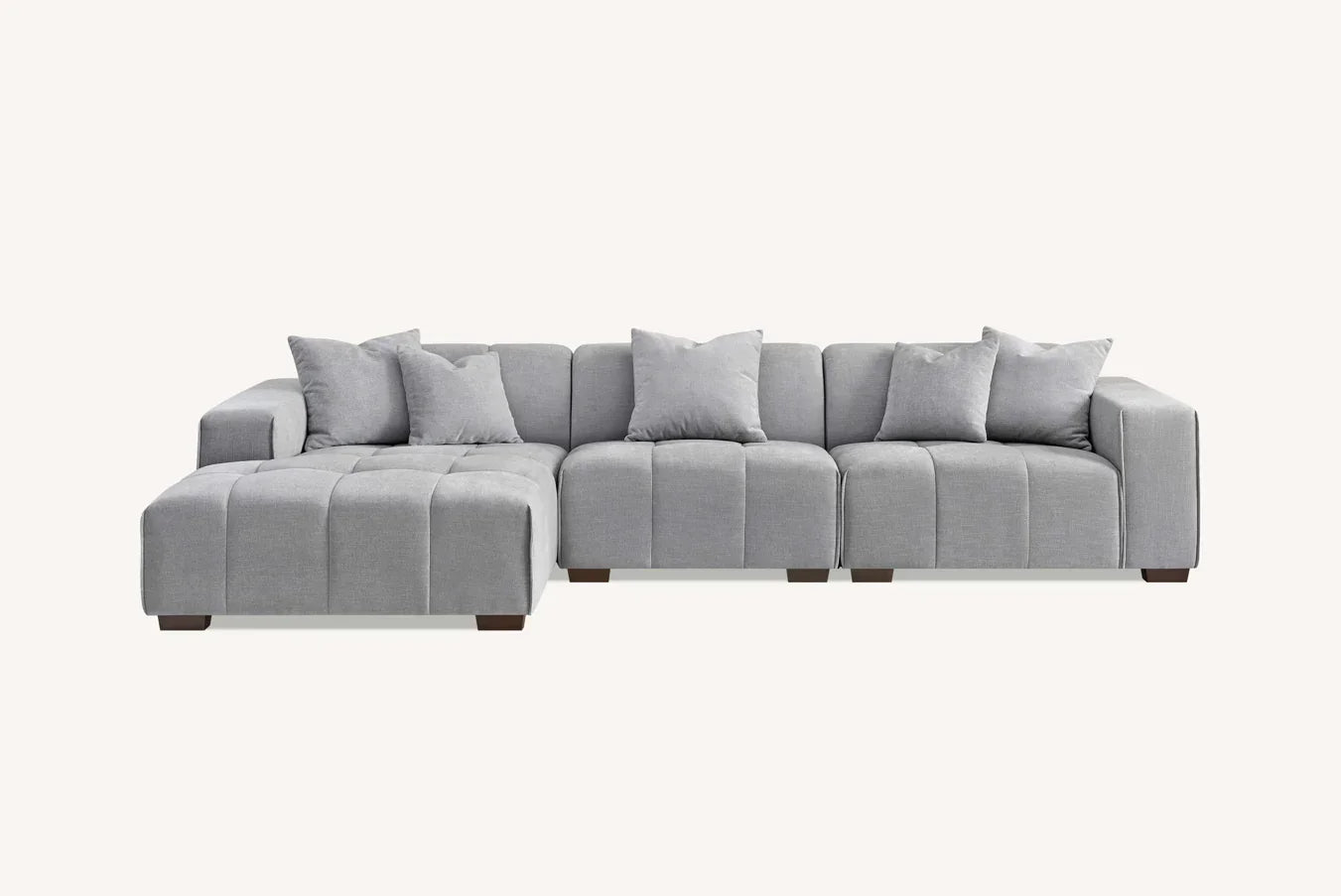 Modern grey fabric corner sofa with chaise and cushions, low wooden legs, front angle view