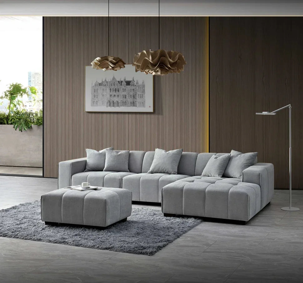 Grey fabric corner sofa with matching ottoman on rug in modern living room