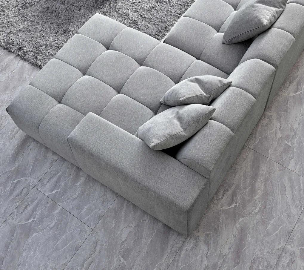 Grey fabric sofa with three cushions on tiled floor beside a shaggy rug, top view
