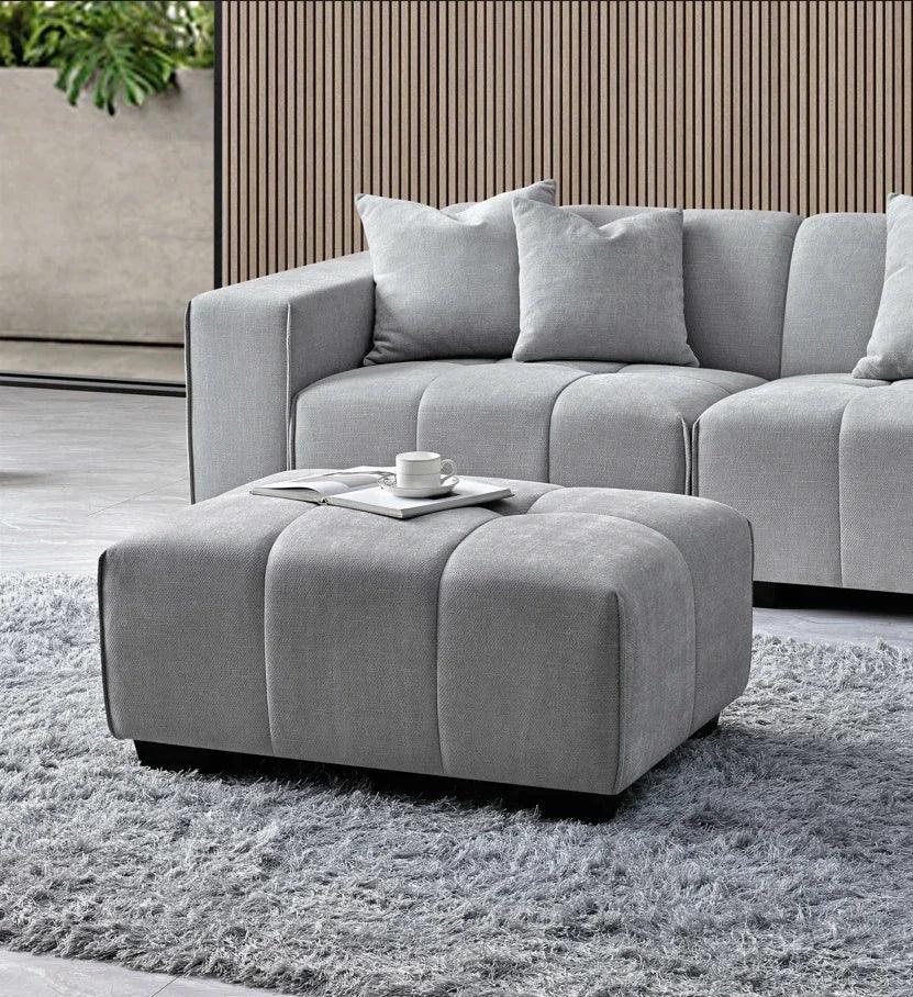 Grey fabric corner sofa set with matching ottoman on shaggy rug in modern living room
