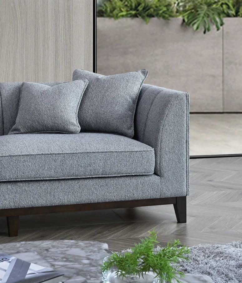 Grey fabric sofa with two matching cushions and dark wood legs in a modern living room