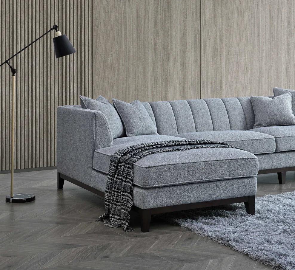 Light grey corner sofa with chaise, tufted back, scatter cushions, and black floor lamp