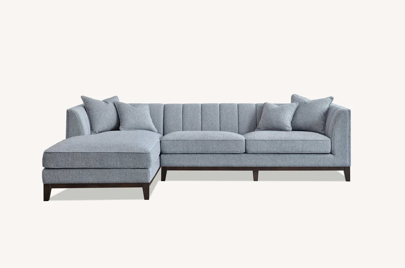 Grey corner sofa with chaise, channel backrest, and matching cushions on dark wood legs