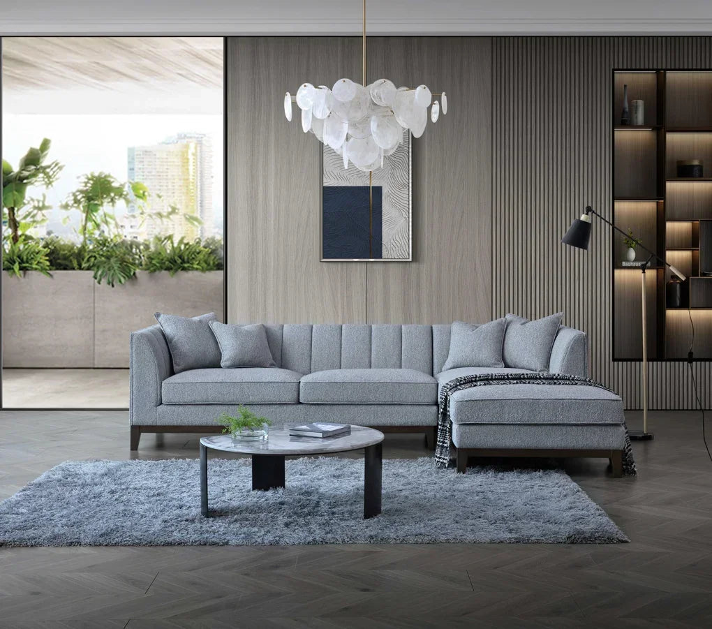 Grey corner sofa with chaise on rug in modern living room, round coffee table in front