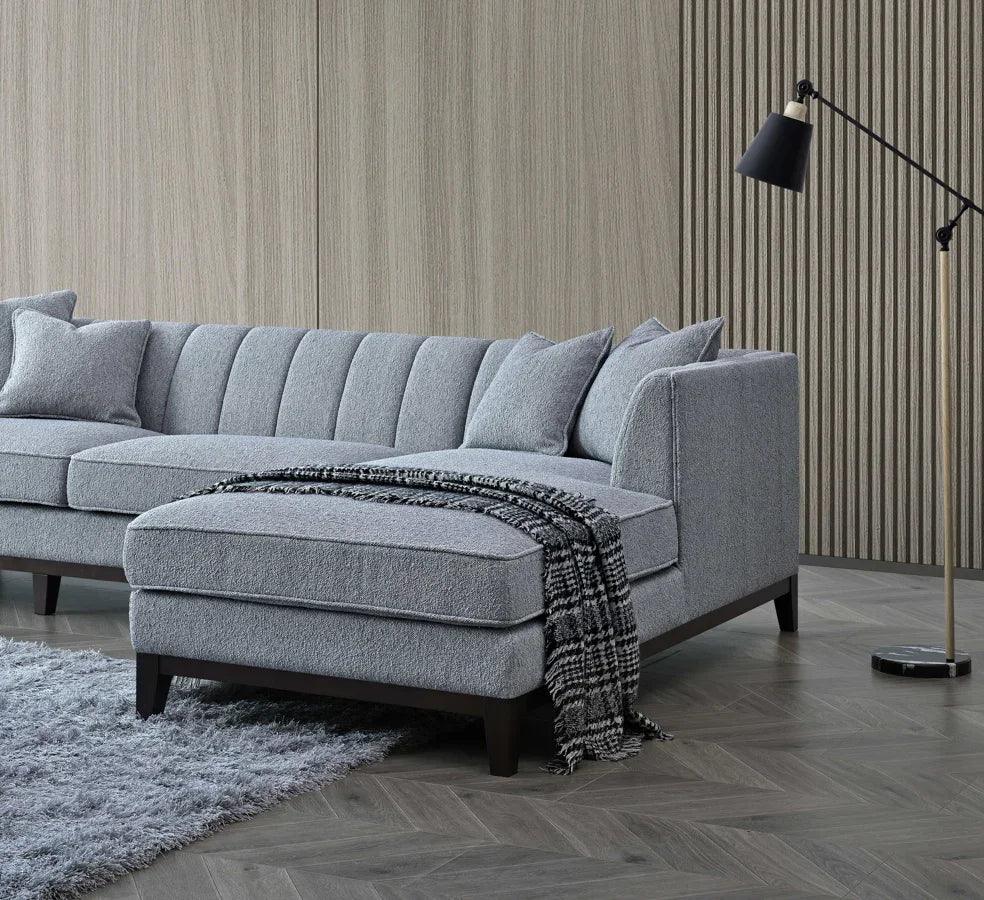 Grey fabric corner sofa with chaise, textured cushions, and plaid throw in modern living room