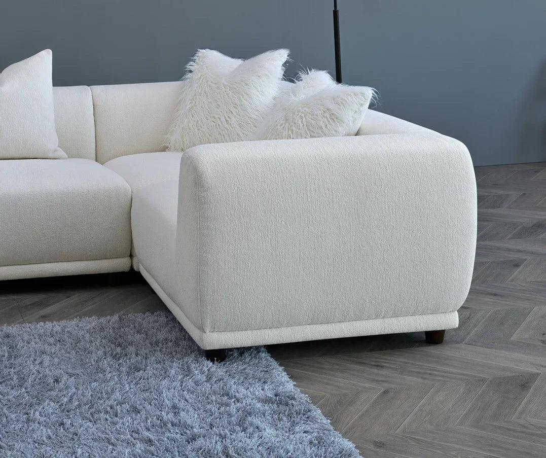 Cream fabric corner sofa with textured cushions on herringbone wood floor and grey rug