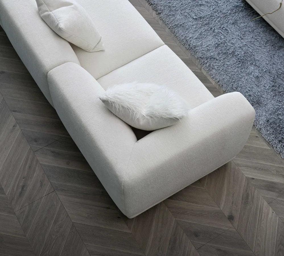 Cream fabric sofa with textured cushions on herringbone wood floor and grey rug